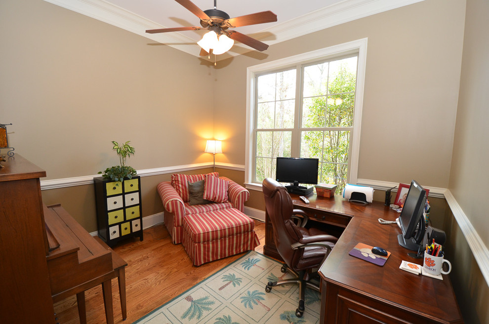 Immagine di un ufficio chic con pareti beige, pavimento in legno massello medio e scrivania autoportante