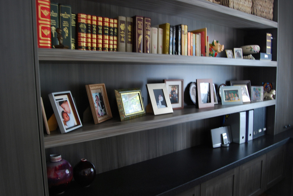 Foto på ett stort funkis hemmabibliotek, med beige väggar, mellanmörkt trägolv och ett inbyggt skrivbord