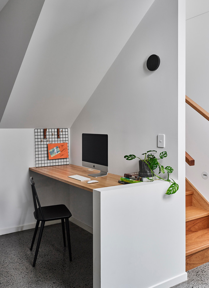 Cette image montre un petit bureau marin avec un mur blanc, aucune cheminée, un bureau intégré et un sol gris.
