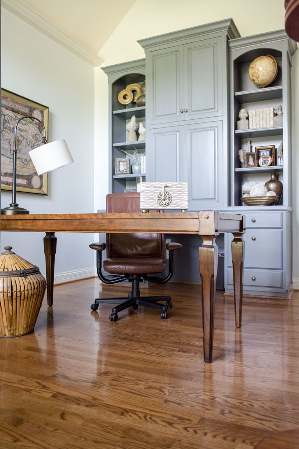 Modelo de despacho tradicional renovado de tamaño medio sin chimenea con paredes azules, suelo de madera en tonos medios, escritorio independiente y suelo marrón