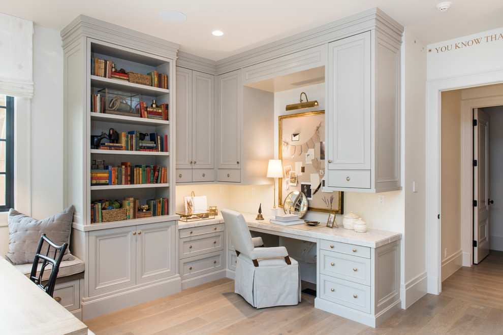 Cette image montre un bureau traditionnel avec un mur blanc, parquet clair, un bureau intégré et un sol beige.