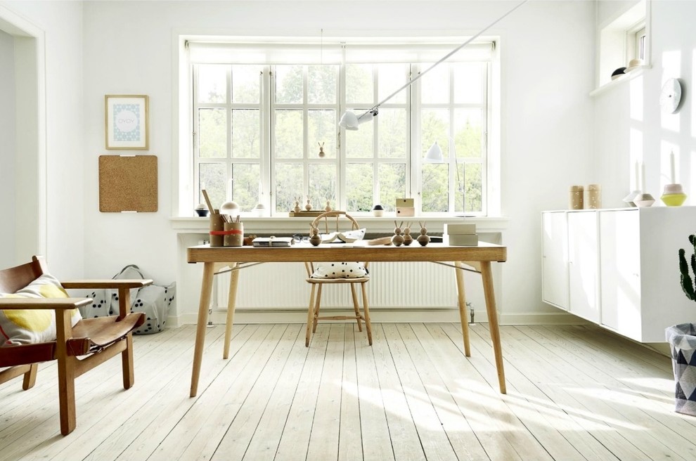 Skandinavisches Arbeitszimmer mit weißer Wandfarbe, hellem Holzboden, freistehendem Schreibtisch und beigem Boden in Richmond