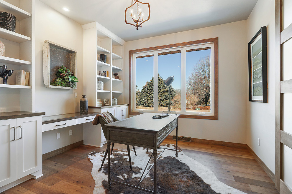 Diseño de despacho ecléctico con paredes grises, suelo de madera en tonos medios, escritorio empotrado y suelo marrón