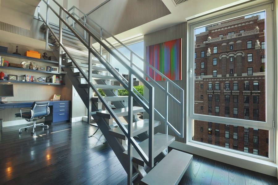 Großes Modernes Arbeitszimmer ohne Kamin mit grauer Wandfarbe, dunklem Holzboden und Einbau-Schreibtisch in New York