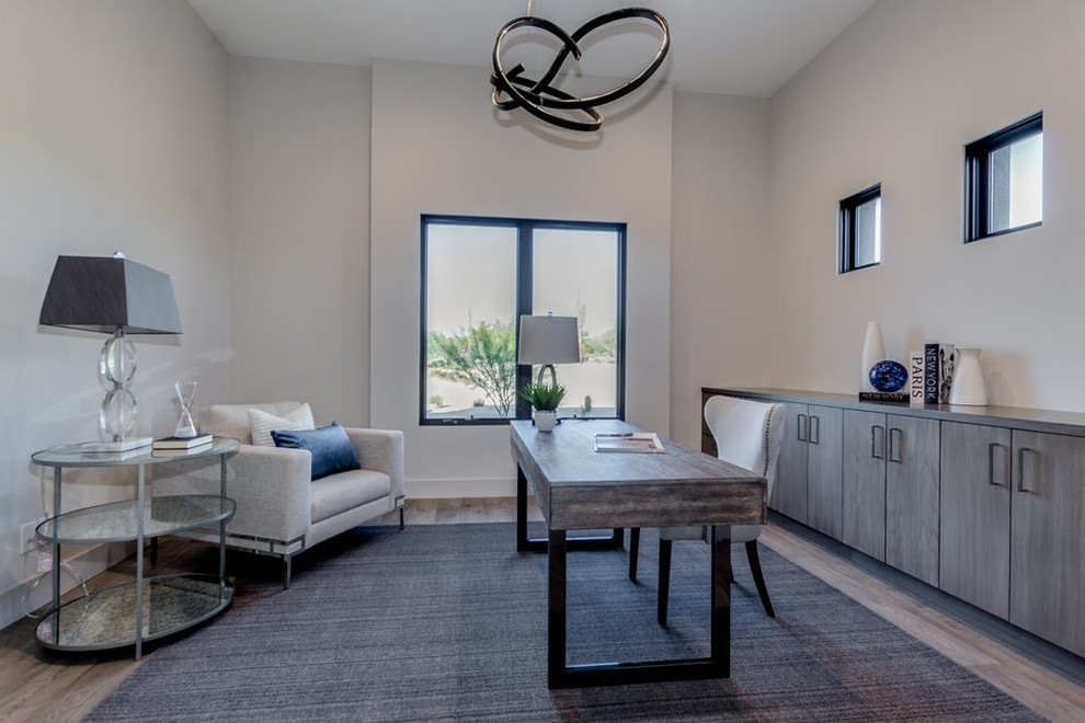 Idee per un ampio ufficio minimalista con pareti bianche, parquet chiaro, scrivania autoportante e pavimento grigio