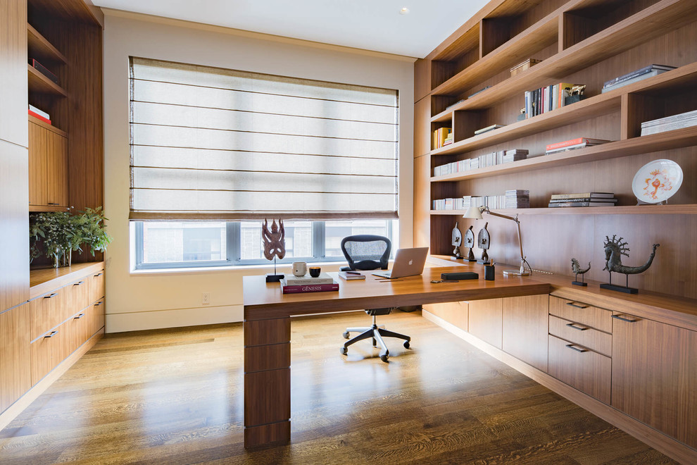 Exemple d'un grand bureau tendance avec un mur blanc, un sol en bois brun, un bureau intégré et un sol marron.