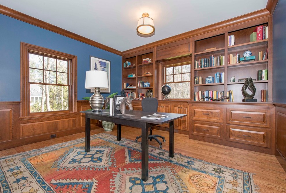 Foto de estudio tradicional grande con paredes azules, suelo de madera en tonos medios y escritorio independiente