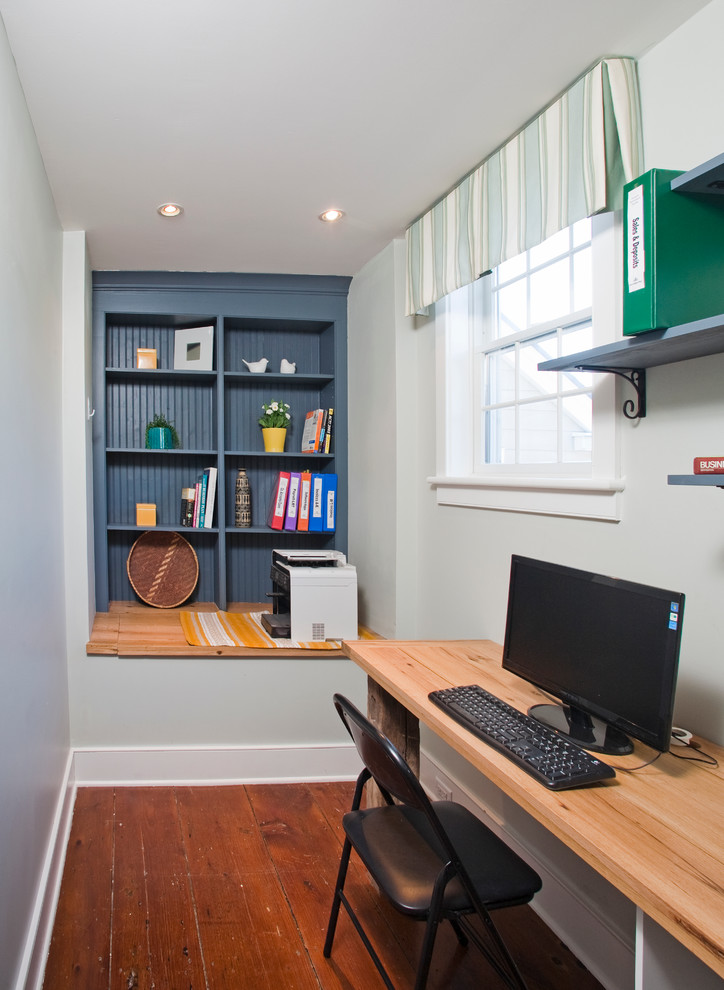 Aménagement d'un petit bureau campagne avec un mur blanc, un sol en bois brun et un bureau indépendant.