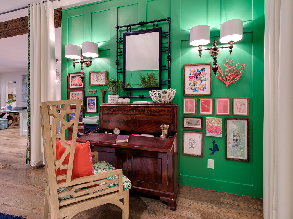 Ejemplo de estudio tropical con paredes verdes, suelo de madera clara y escritorio independiente