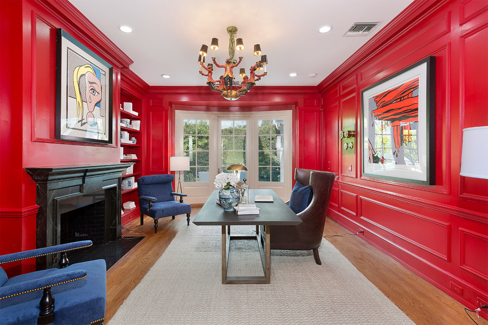 Foto de despacho actual con paredes rojas, suelo de madera en tonos medios, todas las chimeneas, escritorio independiente y suelo marrón