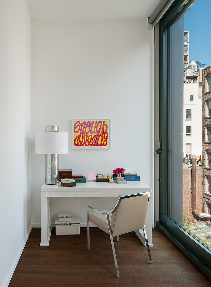 Foto de estudio contemporáneo con paredes blancas, suelo de madera en tonos medios y escritorio independiente