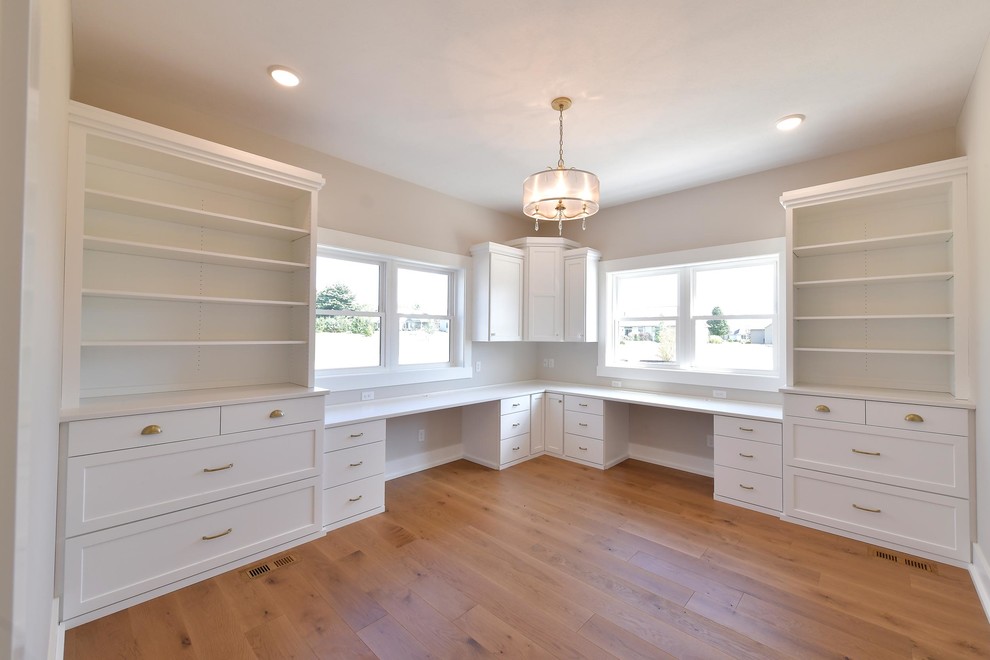 Immagine di una stanza da lavoro classica con pareti bianche, pavimento in legno massello medio e scrivania incassata
