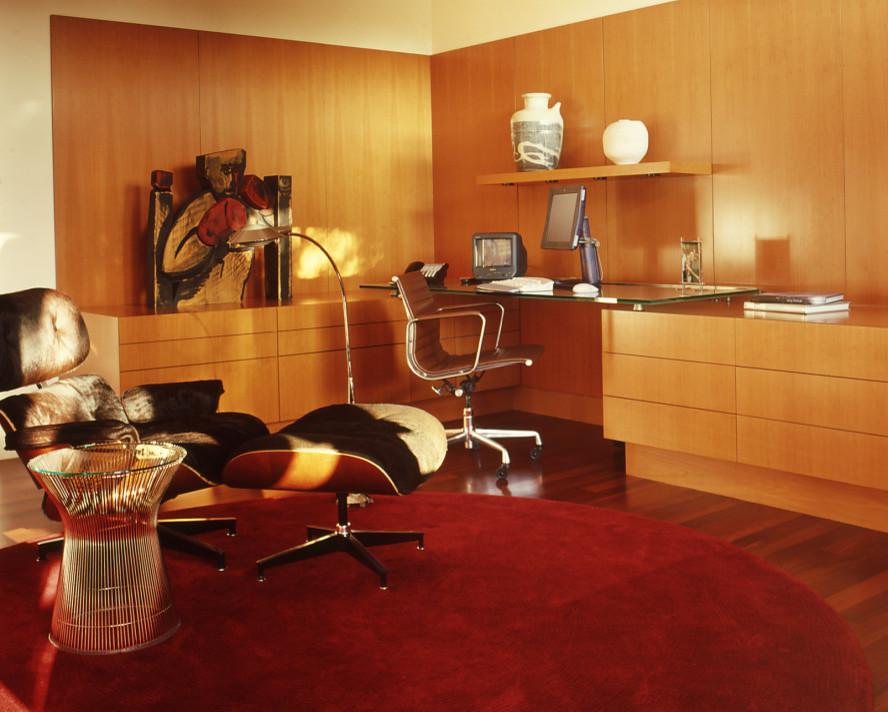 На фото: рабочее место среднего размера в современном стиле с белыми стенами, паркетным полом среднего тона, встроенным рабочим столом и красным полом