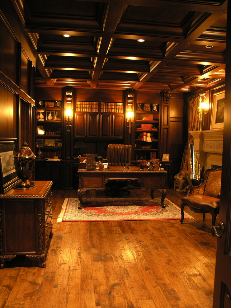 Diseño de despacho tradicional de tamaño medio con paredes beige, suelo de madera en tonos medios, todas las chimeneas, marco de chimenea de yeso, escritorio independiente y suelo marrón