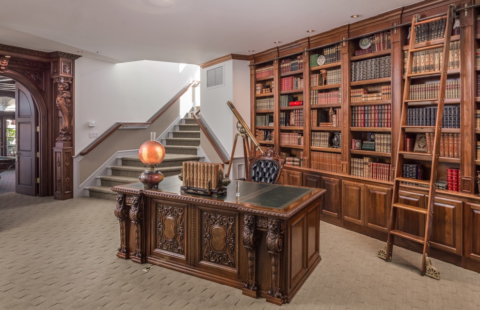 На фото: домашняя библиотека в средиземноморском стиле с ковровым покрытием, отдельно стоящим рабочим столом и бежевым полом с