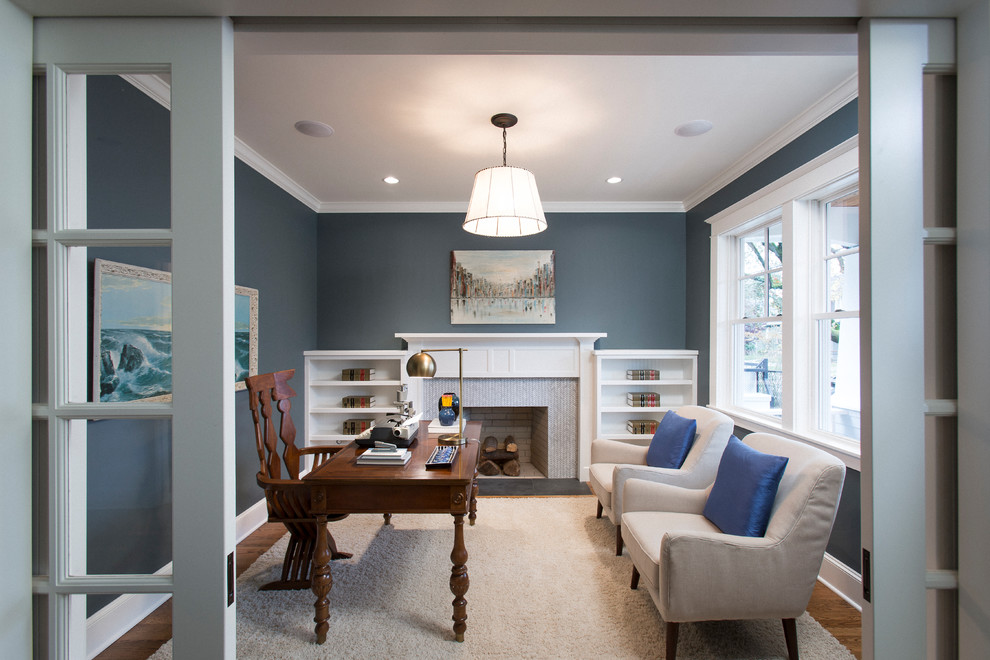 Idée de décoration pour un bureau tradition de taille moyenne avec un mur bleu, un sol en bois brun, une cheminée standard, un manteau de cheminée en carrelage, un bureau indépendant et un sol marron.