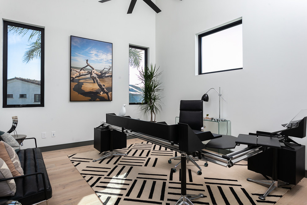 Idéer för ett modernt arbetsrum, med vita väggar, ljust trägolv och ett fristående skrivbord