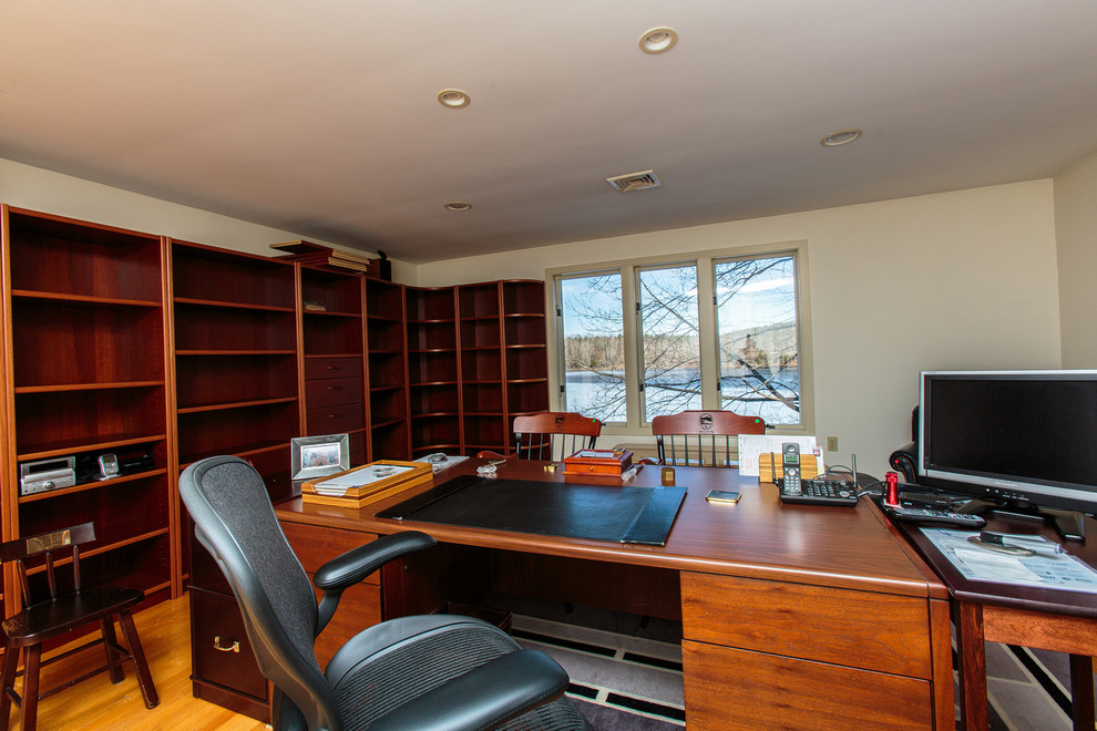 Cette image montre un grand bureau traditionnel avec un mur blanc, un sol en bois brun et un bureau indépendant.