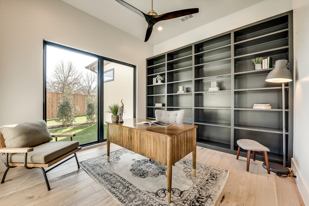 Modelo de despacho minimalista de tamaño medio con paredes beige, suelo de madera clara y escritorio independiente