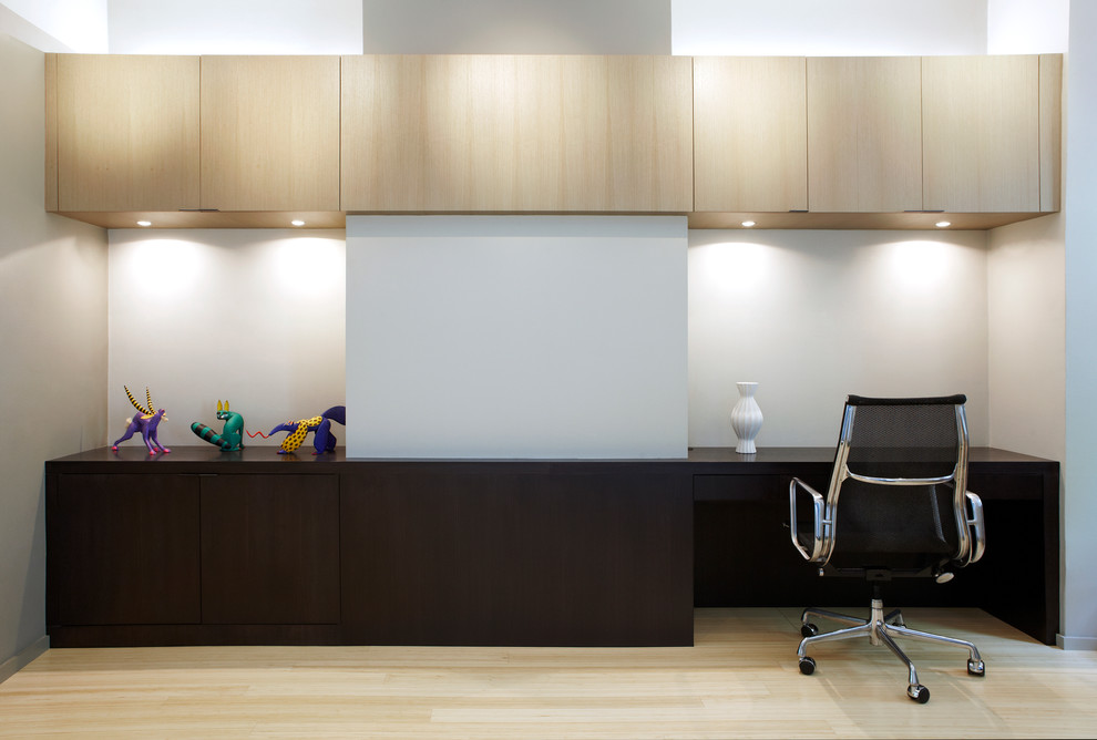 На фото: кабинет в современном стиле с белыми стенами, светлым паркетным полом и встроенным рабочим столом с