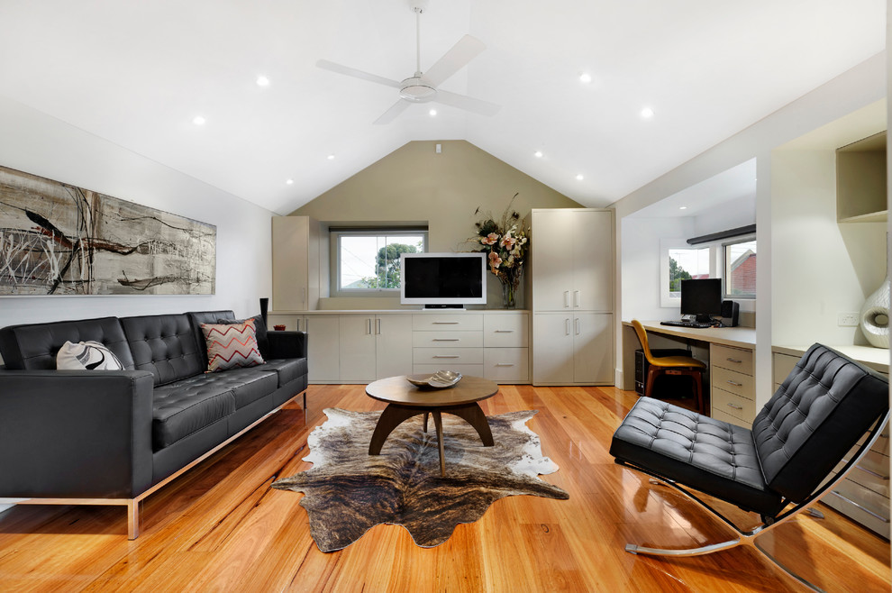 Example of a large trendy built-in desk medium tone wood floor home office design in Melbourne with white walls