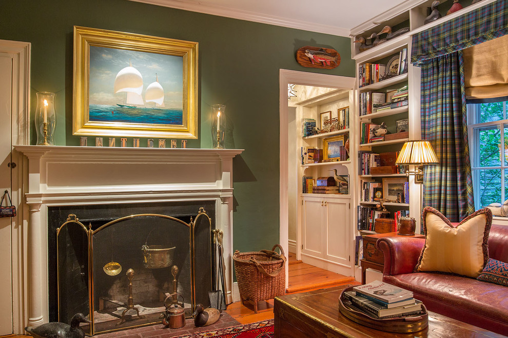 This is an example of a medium sized classic study in New York with green walls, medium hardwood flooring, a standard fireplace, a tiled fireplace surround and a freestanding desk.