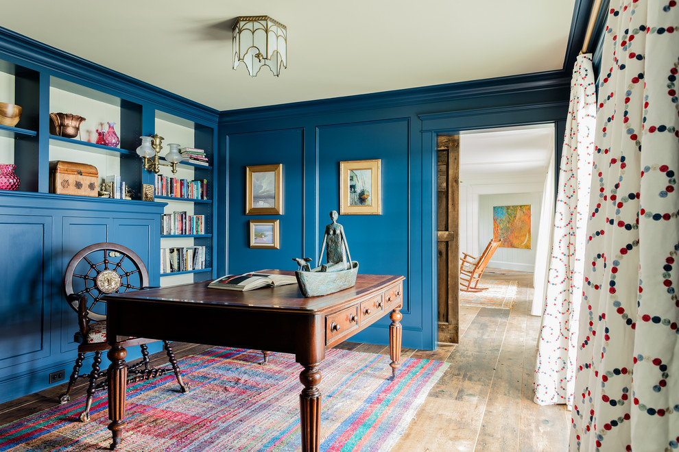 Foto på ett maritimt hemmabibliotek, med blå väggar, ljust trägolv och ett fristående skrivbord