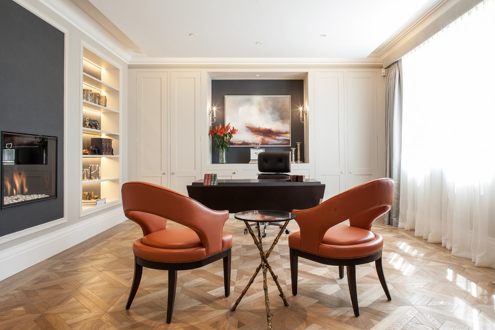 Traditional study in London with light hardwood flooring and a freestanding desk.