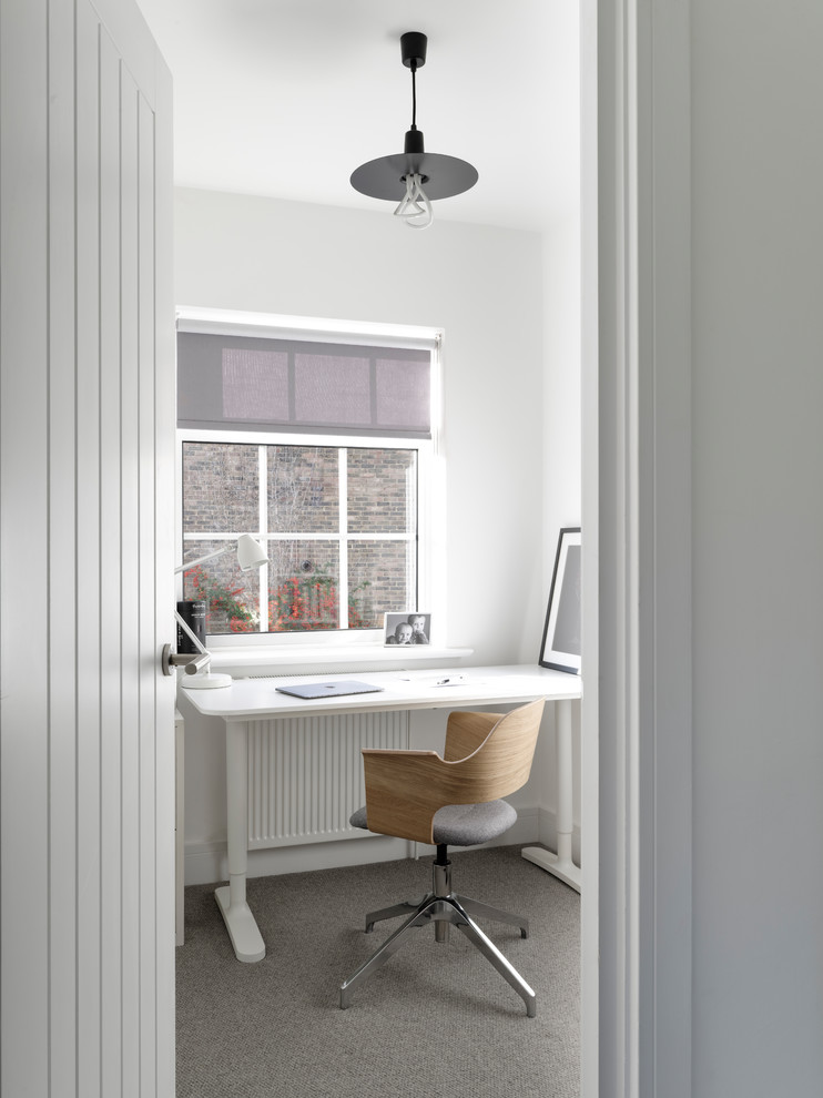 Kleines Modernes Arbeitszimmer mit Arbeitsplatz, weißer Wandfarbe, Teppichboden, freistehendem Schreibtisch und grauem Boden in Sussex