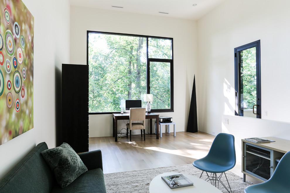 This is an example of a contemporary home office in DC Metro with white walls, light hardwood flooring and a freestanding desk.