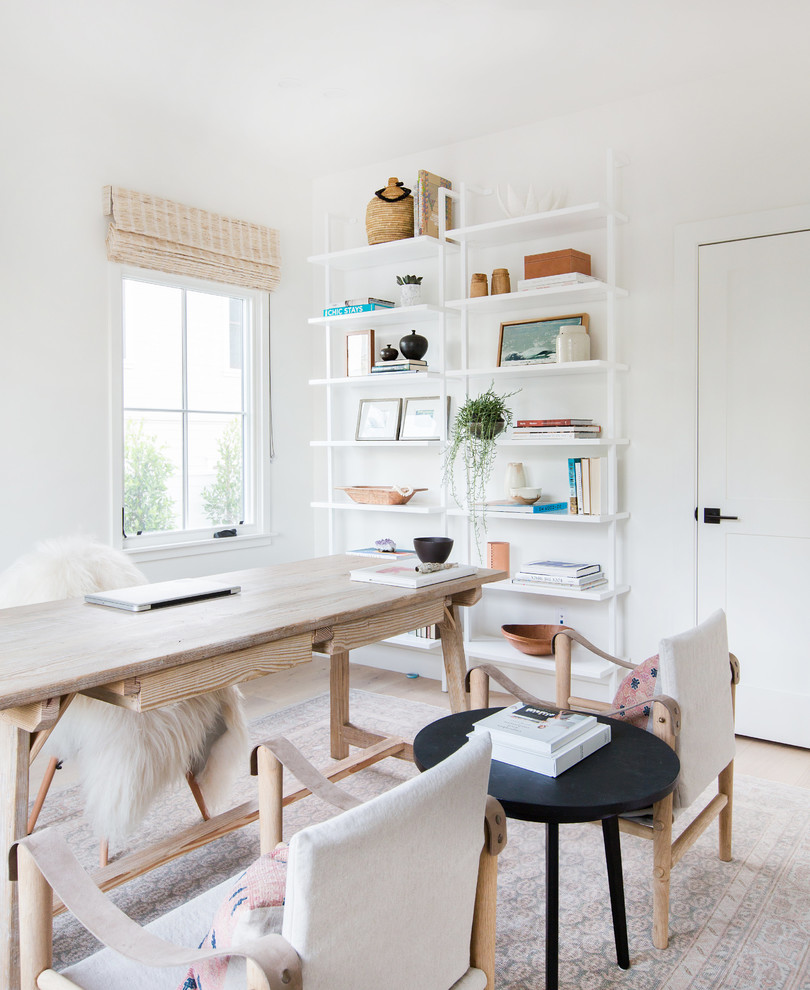 Klassisk inredning av ett arbetsrum, med vita väggar, ljust trägolv och ett fristående skrivbord
