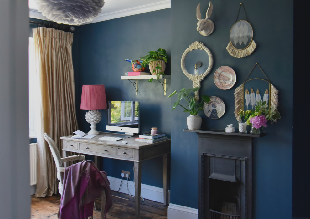 Cette photo montre un bureau éclectique de taille moyenne avec un mur bleu, parquet foncé, une cheminée standard, un manteau de cheminée en métal, un bureau indépendant et un sol marron.