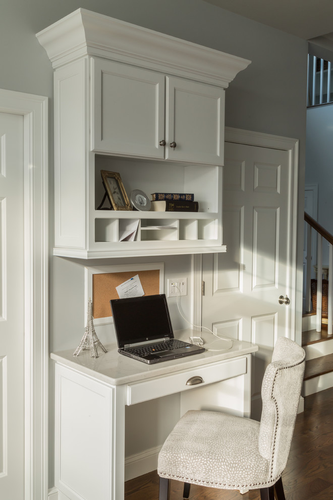 Modelo de despacho tradicional renovado pequeño con paredes grises, suelo de madera oscura y escritorio empotrado