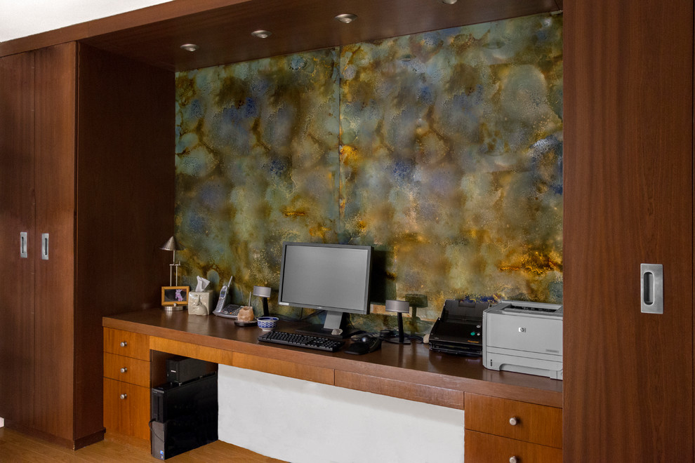 Kleines Arbeitszimmer ohne Kamin mit Studio, weißer Wandfarbe, braunem Holzboden und Einbau-Schreibtisch in New York