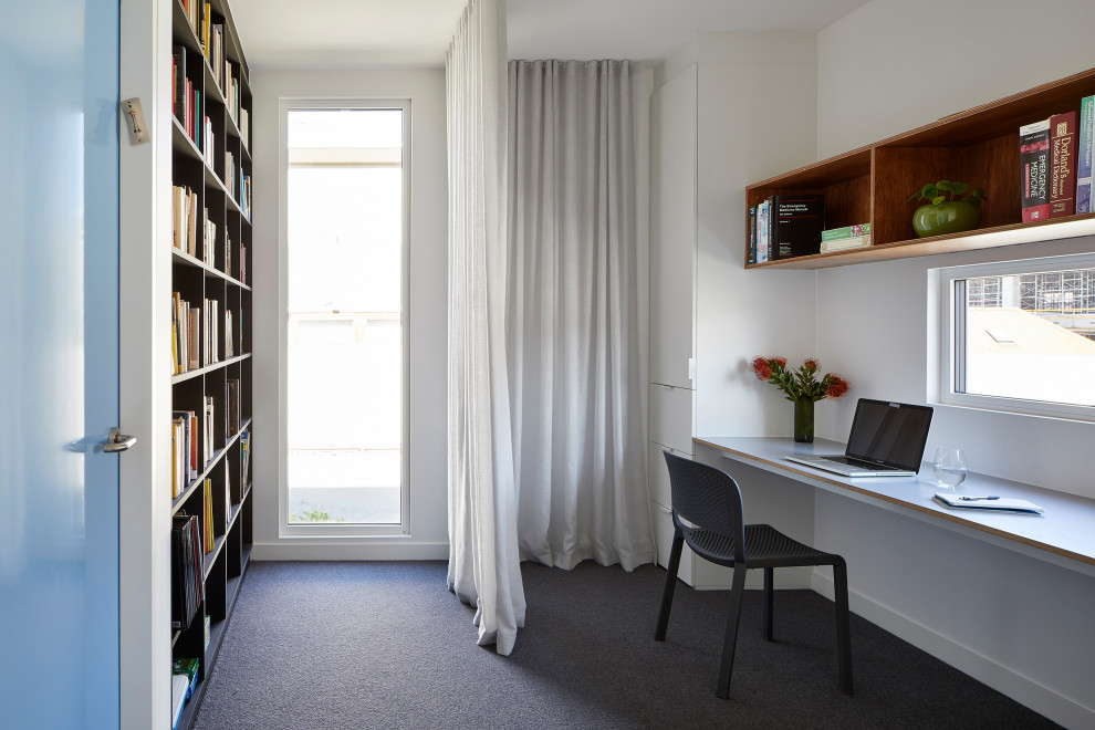 Exempel på ett mellanstort modernt hemmabibliotek, med vita väggar, heltäckningsmatta, ett inbyggt skrivbord och grått golv