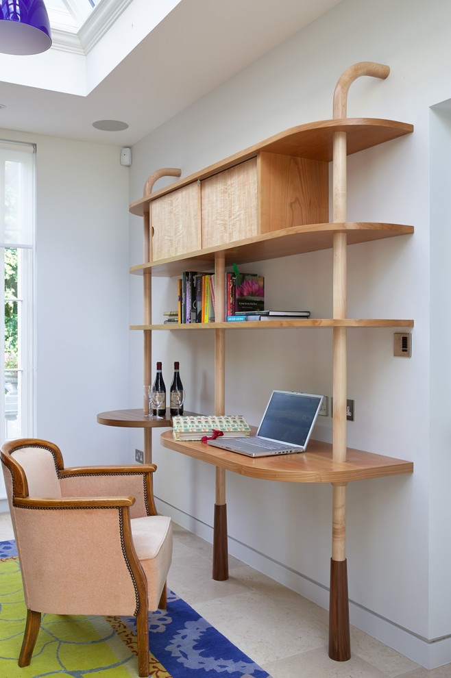This is an example of a contemporary study in London with a built-in desk, white walls and beige floors.