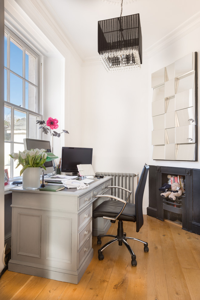 Ispirazione per un ufficio design di medie dimensioni con pareti bianche, pavimento in legno massello medio, camino classico e scrivania autoportante