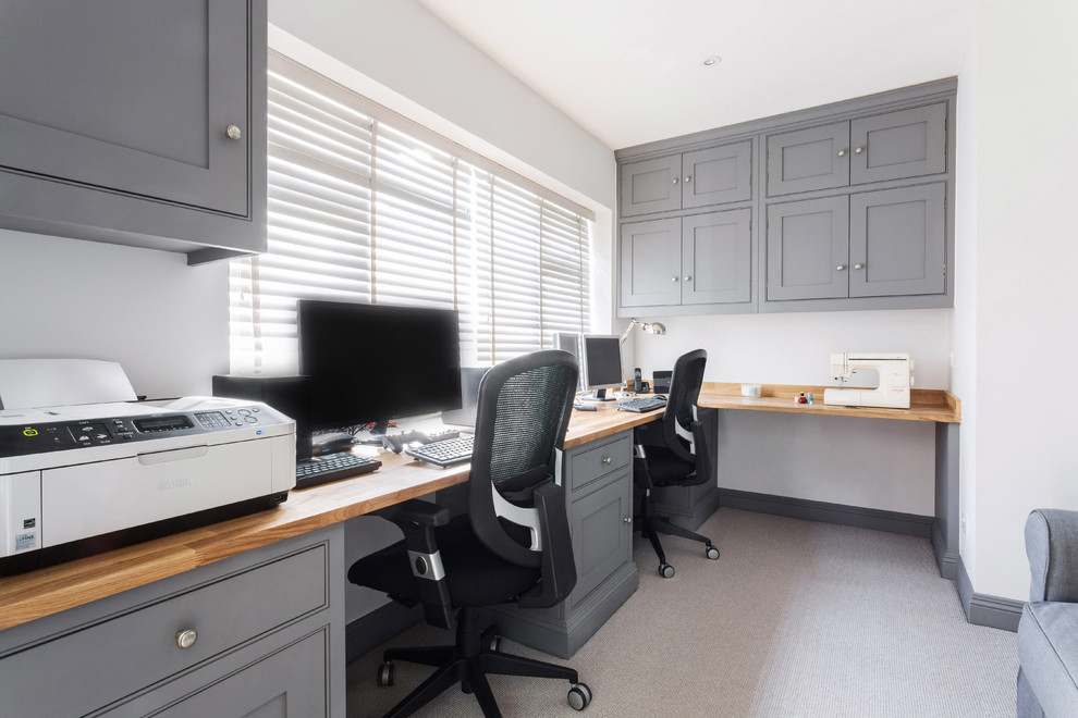 На фото: рабочее место среднего размера в стиле неоклассика (современная классика) с белыми стенами, ковровым покрытием, встроенным рабочим столом и серым полом с