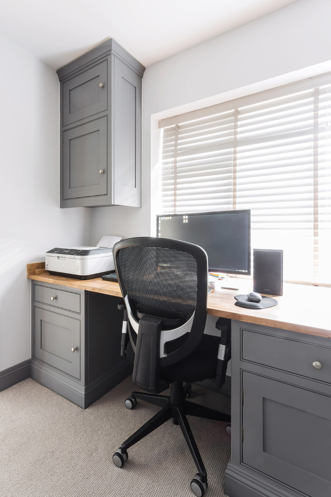 Modelo de despacho clásico de tamaño medio con paredes blancas, moqueta, escritorio empotrado y suelo gris