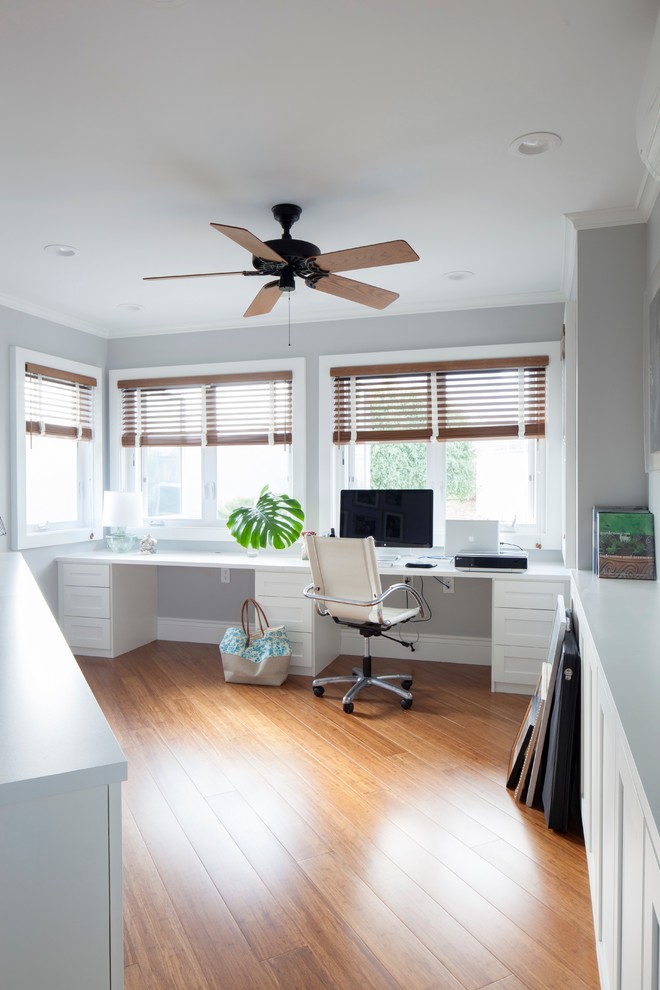 Example of an island style built-in desk medium tone wood floor home office design in Hawaii with gray walls