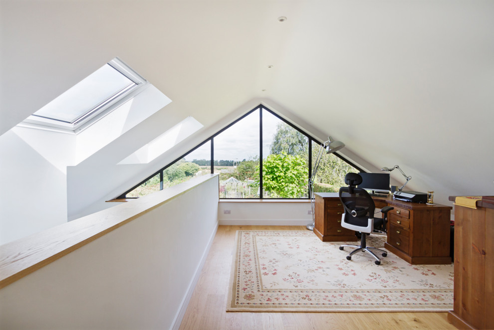 Imagen de despacho abovedado moderno de tamaño medio con paredes blancas, suelo laminado, escritorio independiente y suelo beige