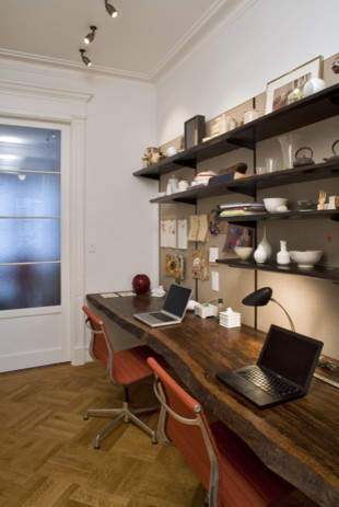 Modelo de despacho bohemio de tamaño medio sin chimenea con paredes blancas, suelo de madera en tonos medios, escritorio empotrado y suelo marrón
