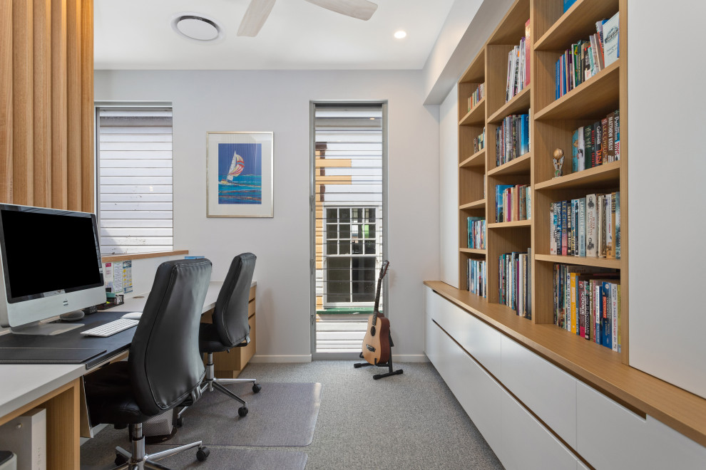 ブリスベンにある小さなビーチスタイルのおしゃれな書斎 (白い壁、カーペット敷き、造り付け机、グレーの床、板張り壁) の写真