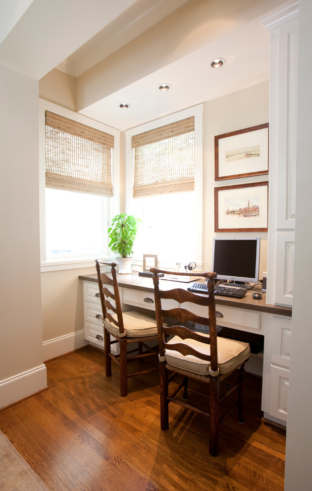 Inspiration pour un grand bureau traditionnel avec un mur beige, un sol en bois brun et un bureau intégré.
