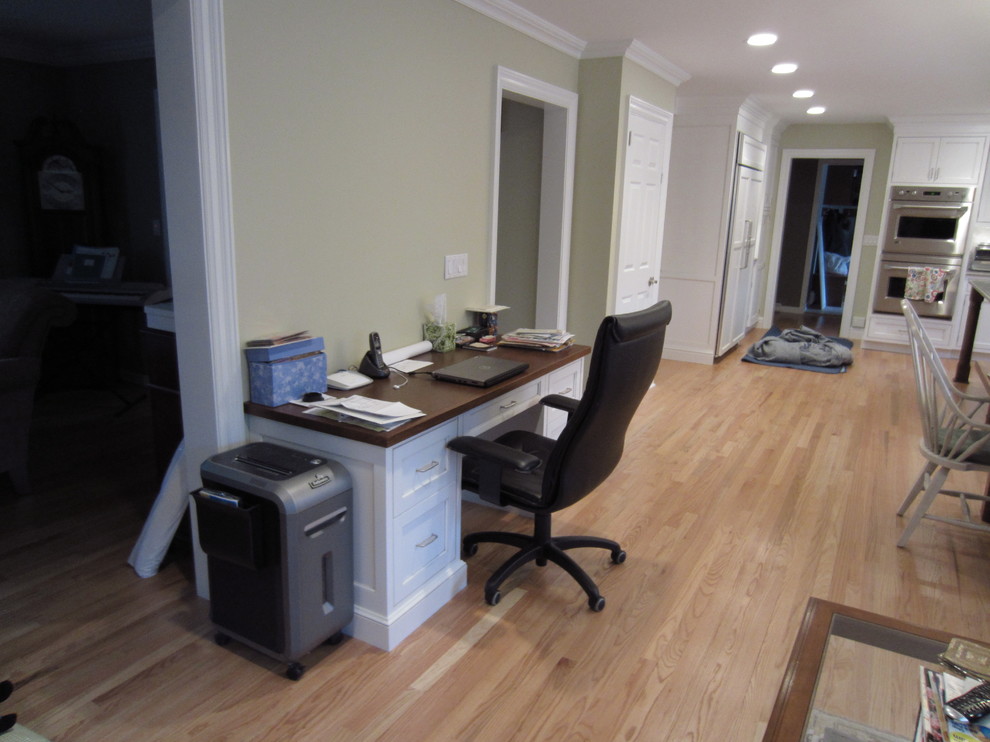 Mittelgroßes Klassisches Arbeitszimmer ohne Kamin mit Arbeitsplatz, beiger Wandfarbe, hellem Holzboden und freistehendem Schreibtisch in New York