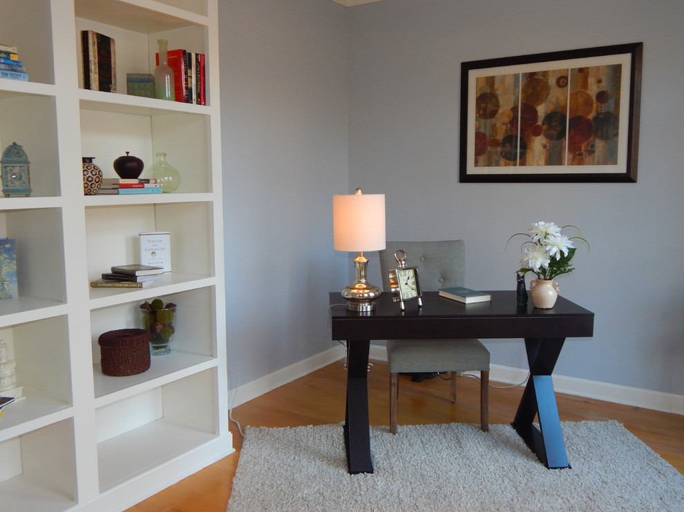 This is an example of a contemporary study in New York with medium hardwood flooring, a freestanding desk and grey walls.