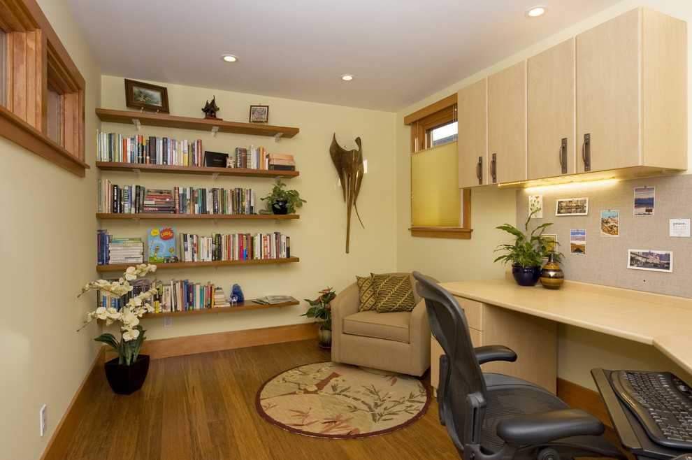Modelo de despacho clásico con biblioteca, suelo de madera en tonos medios, escritorio empotrado y suelo marrón