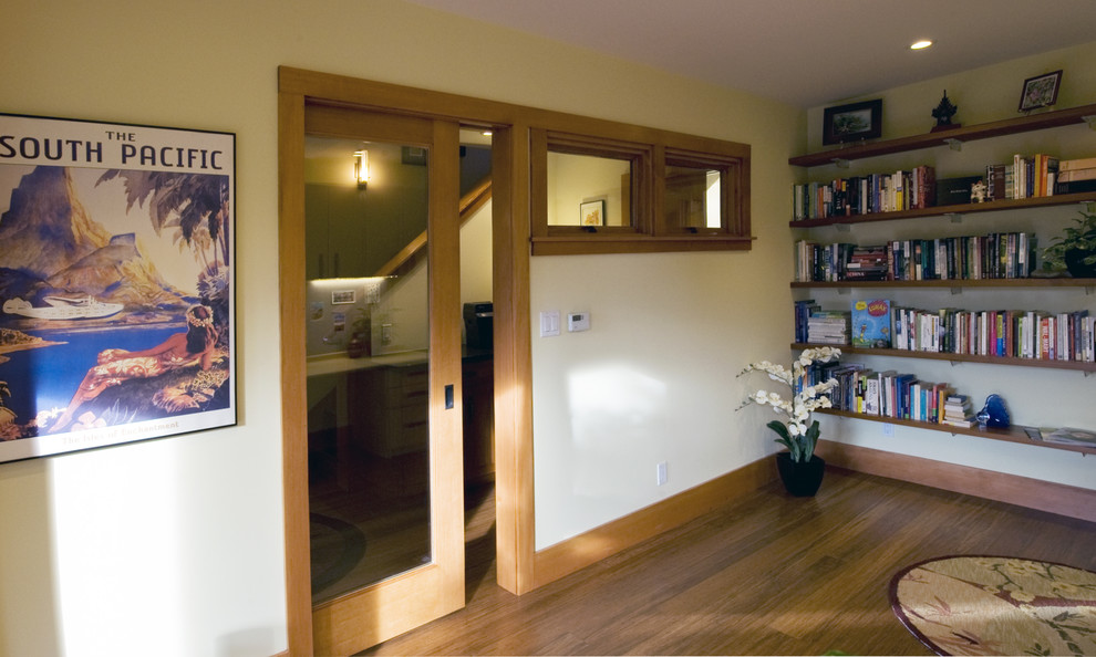 Diseño de despacho tradicional con biblioteca, suelo de madera en tonos medios, escritorio empotrado y suelo marrón
