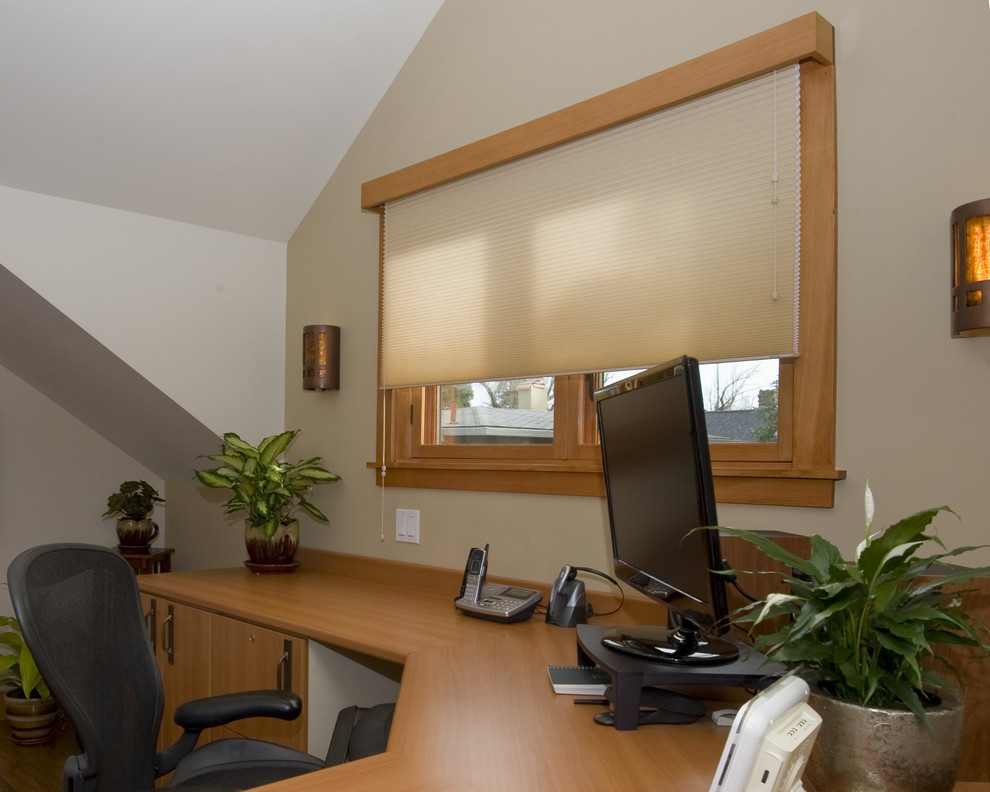 Modelo de despacho tradicional con paredes blancas, suelo de madera en tonos medios, escritorio independiente y suelo marrón