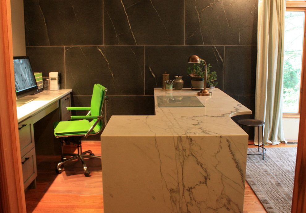 Cette photo montre un grand bureau avec un mur gris et un bureau intégré.